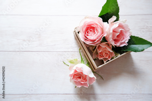 Spring  greeting concept background. Pink roses decoration gift box and rose petals on white wooden table. Spring greeting and spring wedding. ピンクバラのフラワーボックス、結婚式背景、母の日背景 photo