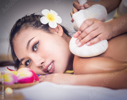 Young Asian woman is taking Thai Herbal ball hot compress massage in an authetic spa authentic photo