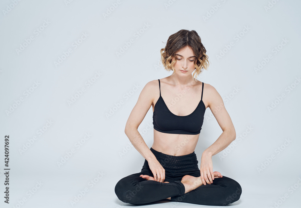 A woman is meditating with her legs crossed on the floor on a light background A woman is meditating with her legs crossed on the floor on a light background