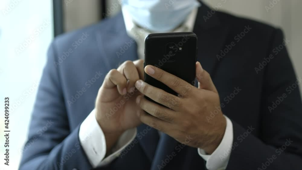 Businessman wearing protection mask using smartphone standing in skytrain. Businessman in urban city travel by sky train. Businessman wearing protection mask using smartphone standing in skytrain. Businessman in urban city travel by sky train.