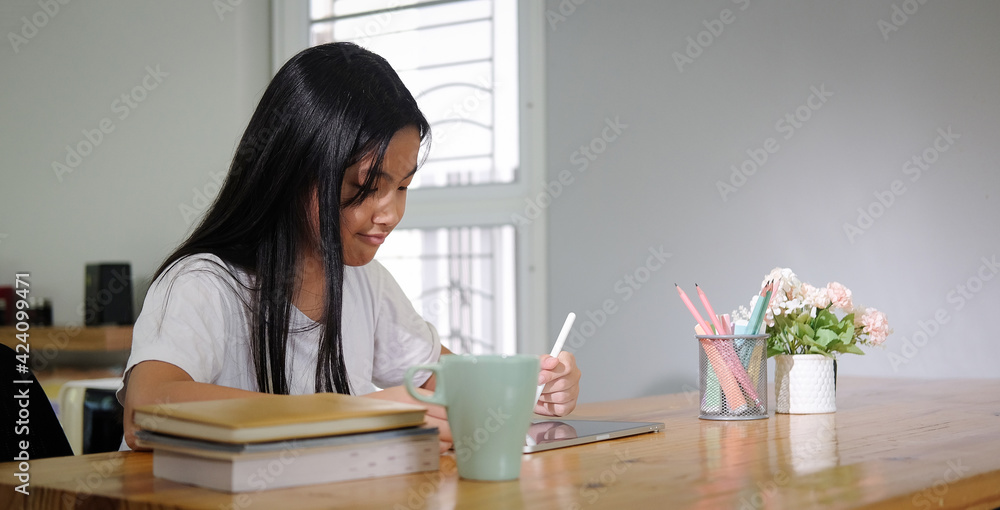 Asian girl student using digital tablet for online lesson at home. Asian girl student using digital tablet for online lesson at home.