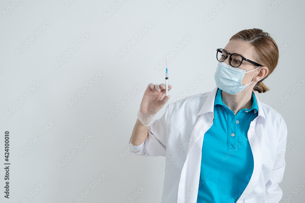 A doctor on a light background holds a syringe with a coronavirus vaccine. defense Pandemic Covid-19 A doctor on a light background holds a syringe with a coronavirus vaccine. defense Pandemic Covid-19
