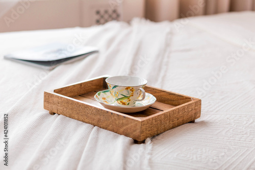 On the bed is a wooden tray with a cup and coffee
