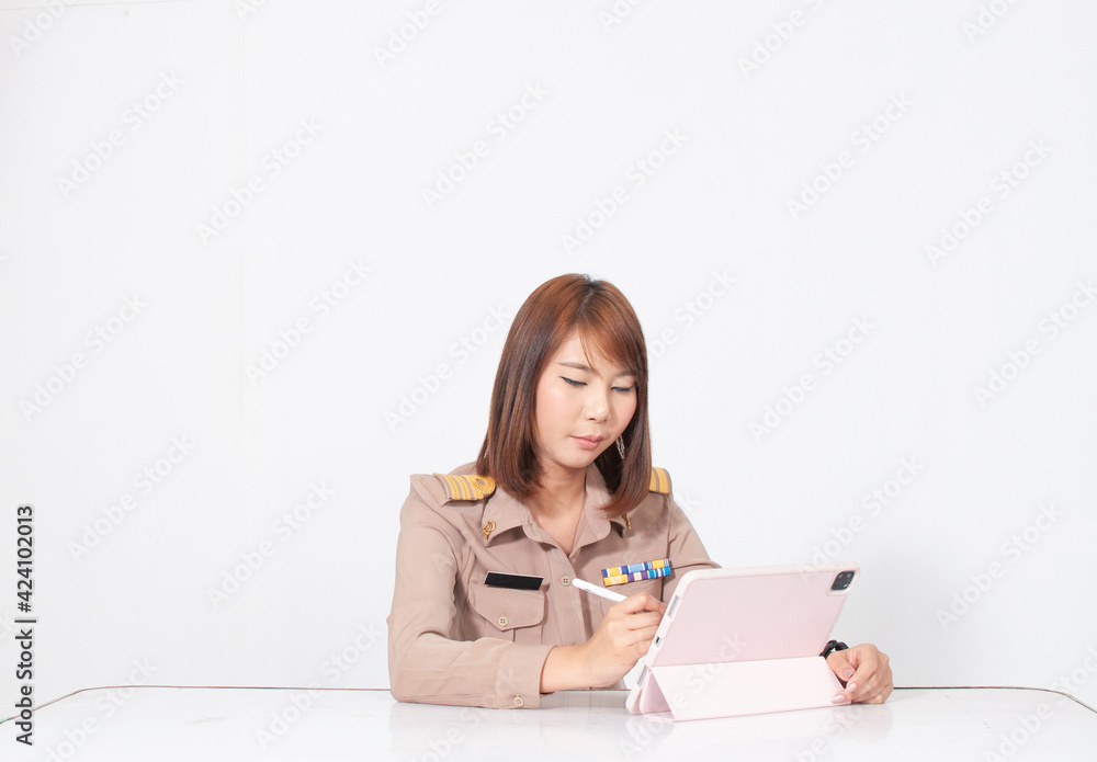 Female thai teacher in uniform sitting with white background writing on tablet Female thai teacher in uniform sitting with white background writing on tablet