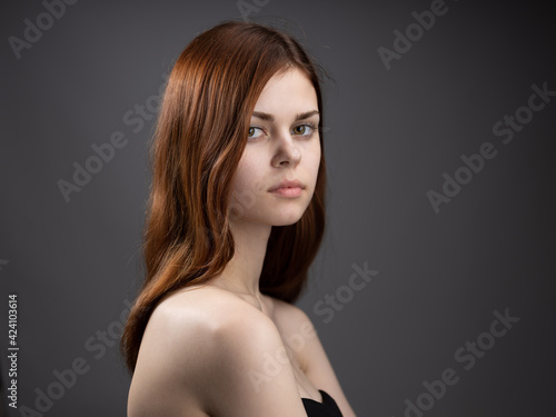 Woman model close-up naked shoulders red hair dark background