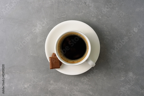 Cup of black coffee with chocolate on grey concrete background