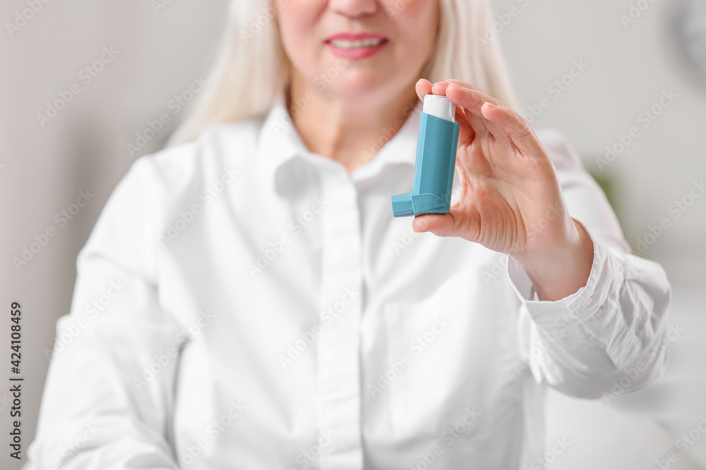 Mature woman with inhaler in office Mature woman with inhaler in office
