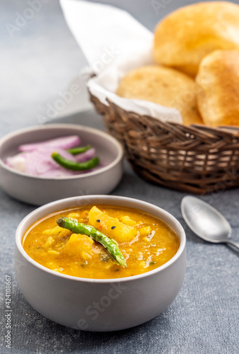 Masala Aloo Sabzi or Indian potato gravy served with fried puri or Poori with sliced onion and green chilly 