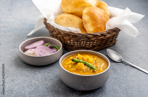 Masala Aloo Sabzi or Indian potato gravy served with fried puri or Poori with sliced onion and green chilly 