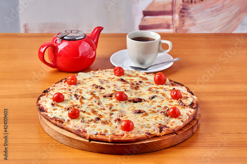 pizza Lombardy lies on a stand with tea and a kettle photo