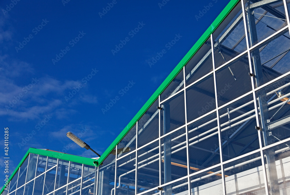 Umea, Norrland Sweden - March 21, 2021: part of a huge greenhouse against the blue sky Umea, Norrland Sweden - March 21, 2021: part of a huge greenhouse against the blue sky