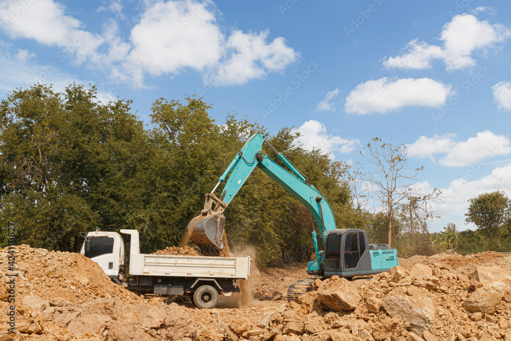 Obraz premium Crawler Excavator digging the soil into a truck ,In the construction site area outdoor .