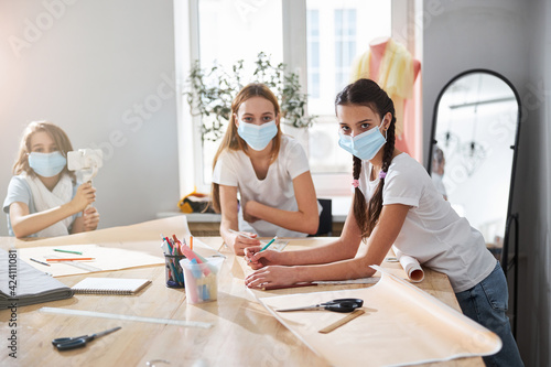 Cute girls in medical masks working in sewing studio