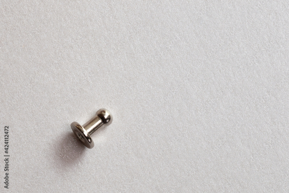 minimalism close-up grommet, rivet, snap, button on the paper silver background. minimalism close-up grommet, rivet, snap, button on the paper silver background.