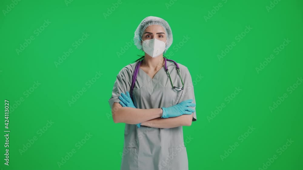 Portrait of young female doctor in protective gear and medical mask, woman looks at the camera, protection from a covid-19, serious look at the camera on a chroma key background.. Portrait of young female doctor in protective gear and medical mask, woman looks at the camera, protection from a covid-19, serious look at the camera on a chroma key background..