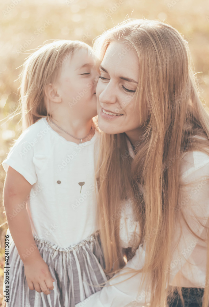 Obraz premium little daughter kissing mom in the park