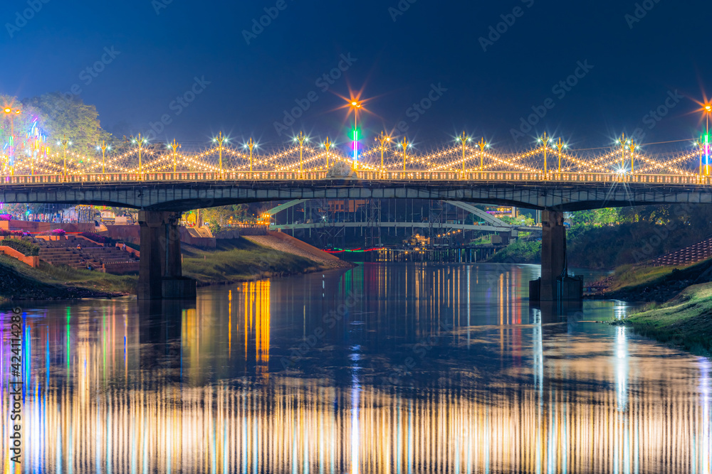 Fototapeta premium Beautiful light on the Nan River at night on the bridge (Naresuan Bridge) on the Road in Realm for Naresuan the Great Festival and Red Cross Annual event in Phitsanulok,Thailand.