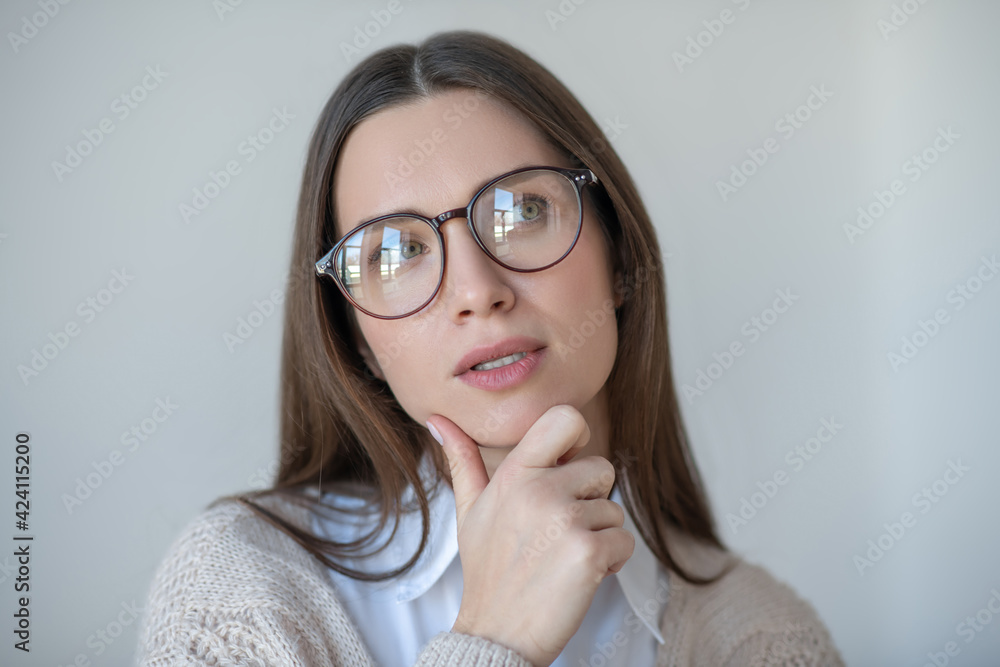 Headshot of long-haired woman in eyeglasses looking thoughtful
