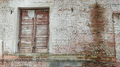 Facade of old abandoned bricks wall with broken weathered wooden door