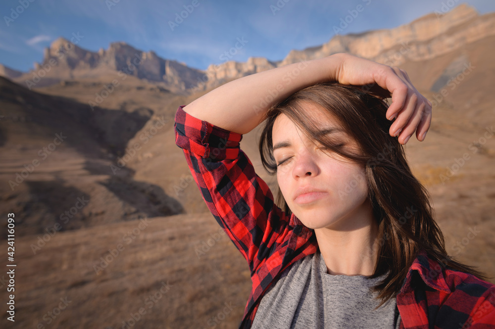 young attractive woman stands in a shirt against a background of mountains young attractive woman stands in a shirt against a background of mountains