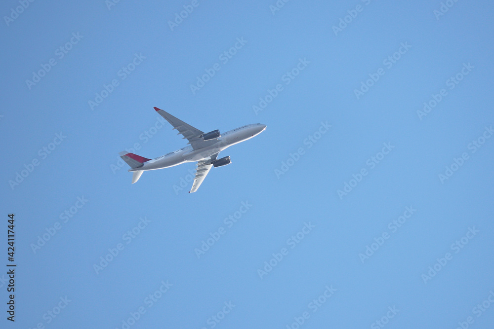 Airplane flying in the clear blue sky, bottom and side view. Commercial plane taking off and gaining altitude Airplane flying in the clear blue sky, bottom and side view. Commercial plane taking off and gaining altitude