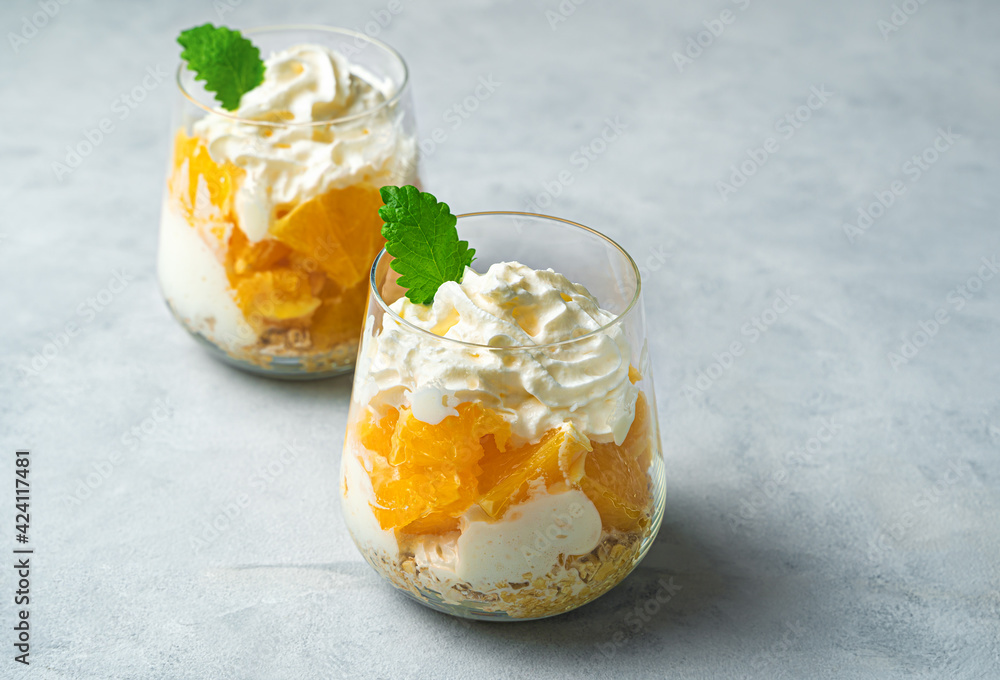 Fruit and cream dessert on a gray background. Orange, cream, and cereal flakes. Fruit and cream dessert on a gray background. Orange, cream, and cereal flakes.