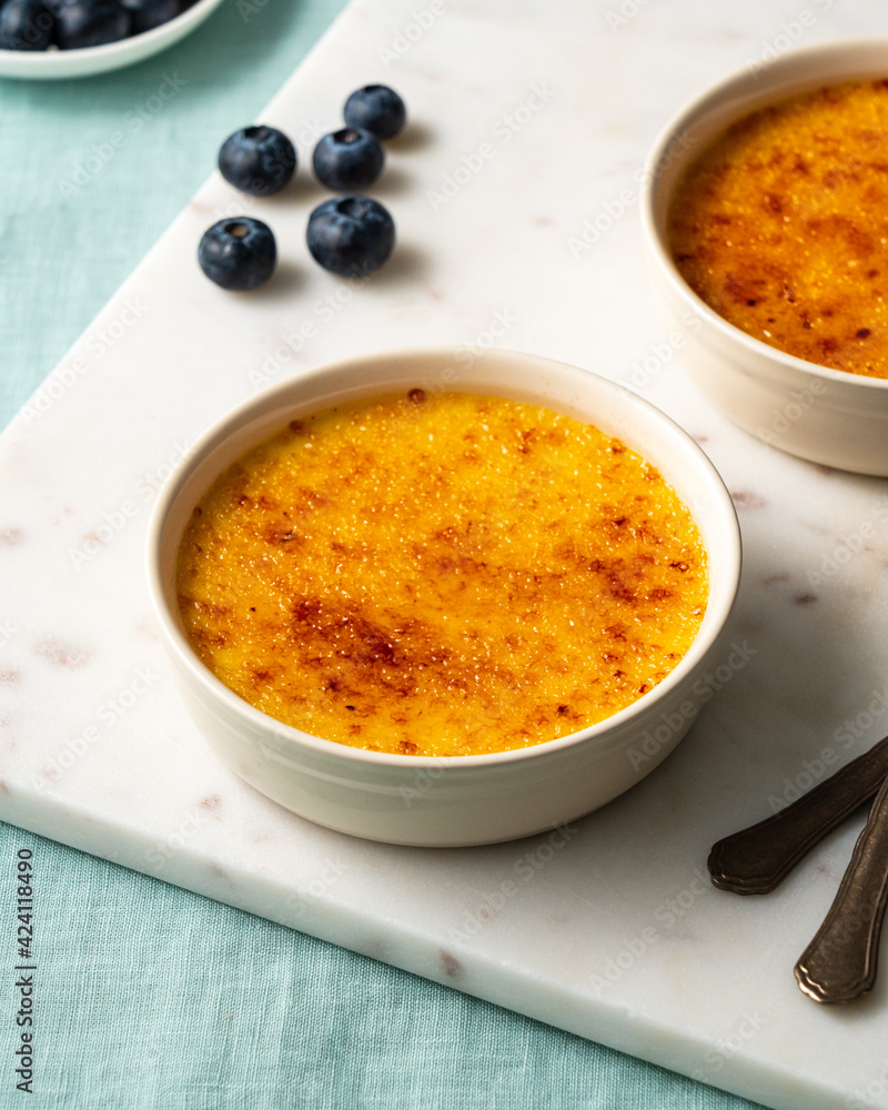 Ramekin with Spanish crema catalana. Traditional French vanilla Creme brulee dessert. Burned cream, burnt or Trinity creme. Rich custard base topped hardened caramelized sugar. Side view, vertical Ramekin with Spanish crema catalana. Traditional French vanilla Creme brulee dessert. Burned cream, burnt or Trinity creme. Rich custard base topped hardened caramelized sugar. Side view, vertical