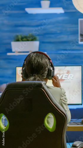 Angry african pro woman gamer losing space shooter videogame during online championship. Cyber player testing virtual video games using powerful personal computer in gaming room during esports photo