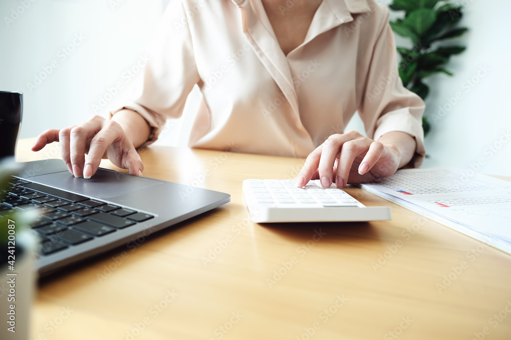 Business woman using calculator to review balance sheet annual using document and laptop computer to calculating budget. audit and Check integrity before investment concept. Business woman using calculator to review balance sheet annual using document and laptop computer to calculating budget. audit and Check integrity before investment concept.