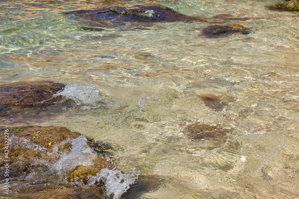 Water splashing on a rock near a jellyfish in the water at Prajjet Bay in Malta on a warm fall day.