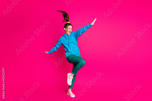 Full length photo of cute sweet lady wear blue sweater dancing standing one leg hands sides isolated bright pink color background © deagreez