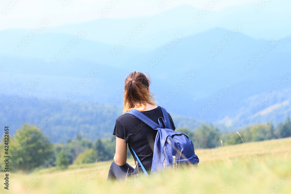 The girl on the top with a backpack the traveler enjoys in the summer and looks at the mountains. Wildlife. Carpathians.