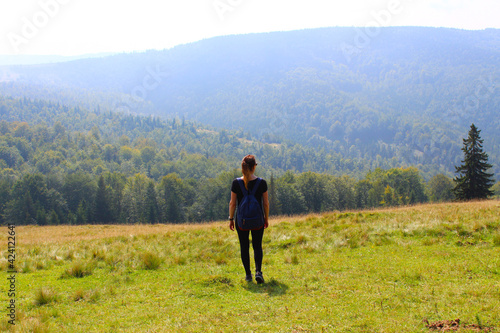 The girl with a backpack the traveler enjoys in the summer and looks at the mountains. Wildlife. Carpathians.