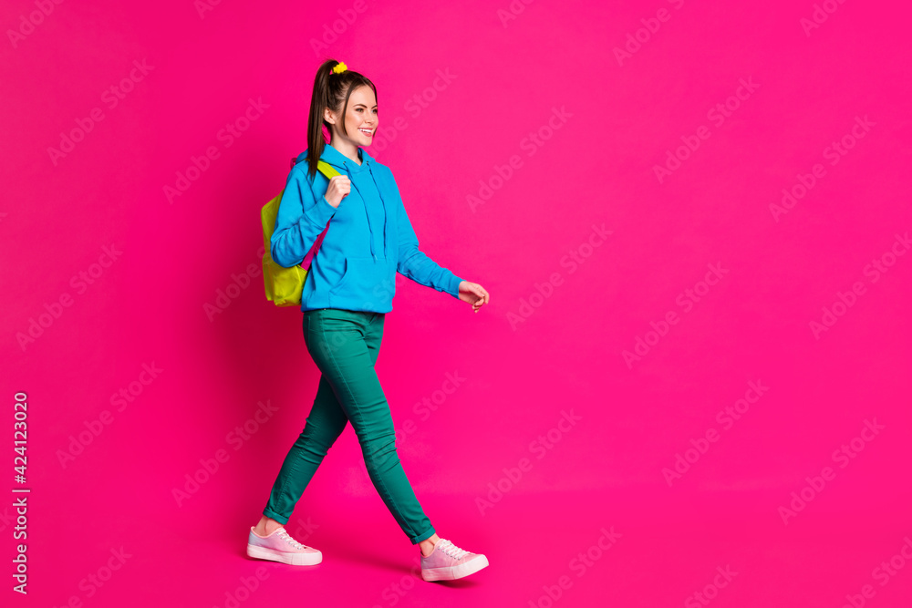 Full length photo of sweet young lady wear blue sweater rucksack walking looking empty space isolated bright pink color background