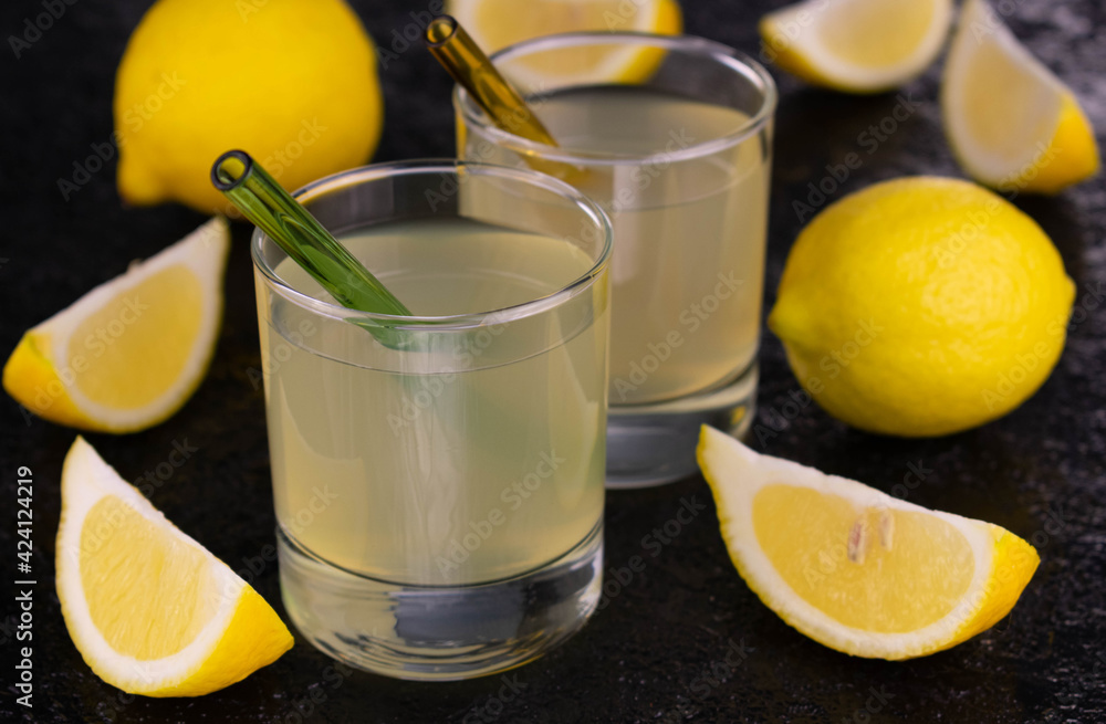 Two glasses of fresh lemon juice on a black background. Close-up. Two glasses of fresh lemon juice on a black background. Close-up.