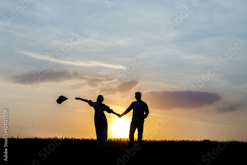 Silhouette of a young couple, a girl throws a hat to the side