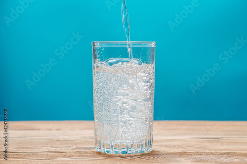 Pure carbonated water with bubbles in a glass on a blue background