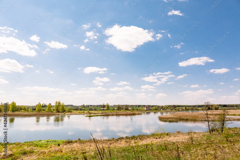 Beautiful summer landscape. A scene with a river and village in the distance. Recreational area. Sunny warm weather. Flat terrain. Lake in Belarus. Travel to natural places. Wallpaper natural design