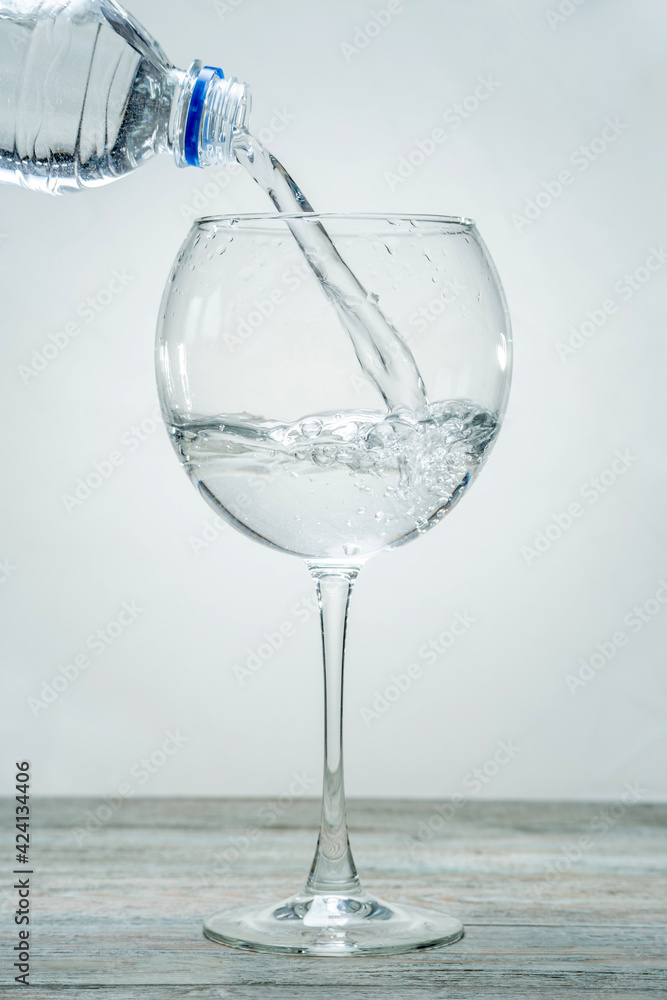 In a beautiful elegant glass on a stem is pouring from a bottle of clean healthy water