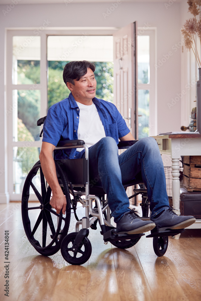 Mature Asian Man In Wheelchair Pushing Himself Along Hallway At Home Mature Asian Man In Wheelchair Pushing Himself Along Hallway At Home