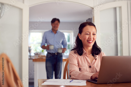 Slika na platnu Mature Asian Couple At Home Using Laptop To Organise Household Bills And Finance