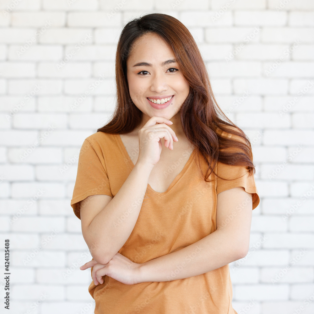 Young and beautiful healthy Asian woman using hand touch a chin with a friendly face and positive pose on a plain background. Concept for joy, proud, self-confident, and successful female Young and beautiful healthy Asian woman using hand touch a chin with a friendly face and positive pose on a plain background. Concept for joy, proud, self-confident, and successful female