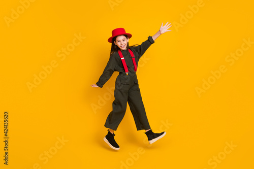 Full length body size view of pretty cheerful girl jumping having fun walking strolling isolated over bright yellow color background