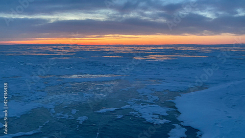 Amazing sunset on the northern frosty lake Baikal. Panorama of the northern landscape of the frozen lake.