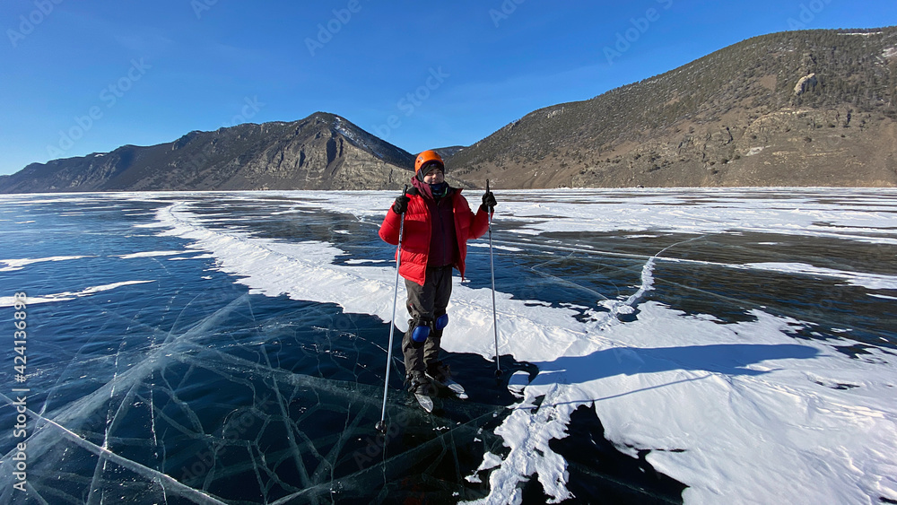 A traveler guy stands on skates on the ice of frozen Lake Baikal.