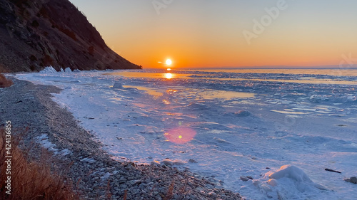 Amazing sunrise on the northern frosty Lake Baikal. Panorama of the northern landscape of the frozen lake.