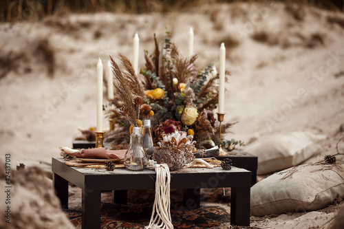 A table  designed for a boho style event with an eucalyptus, vintage plates and other rustic touches. On seaside in the sand