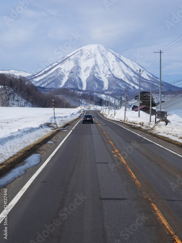 Snow-capped volcano beyond a road  Mount Yotei  Hokkaido  Japan 