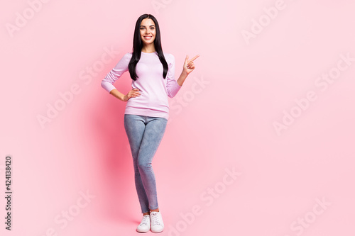 Full size photo of young beautiful happy positive smiling girl advertising point finger copyspace isolated on pink color background