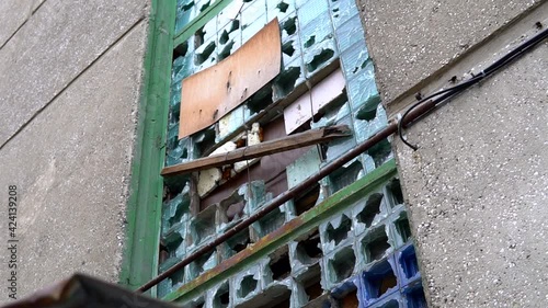 Abandoned building wall with broken windows. Old, deserted dormitory apartment. Rough criminal distrist, low angle pan and tilt shot. photo